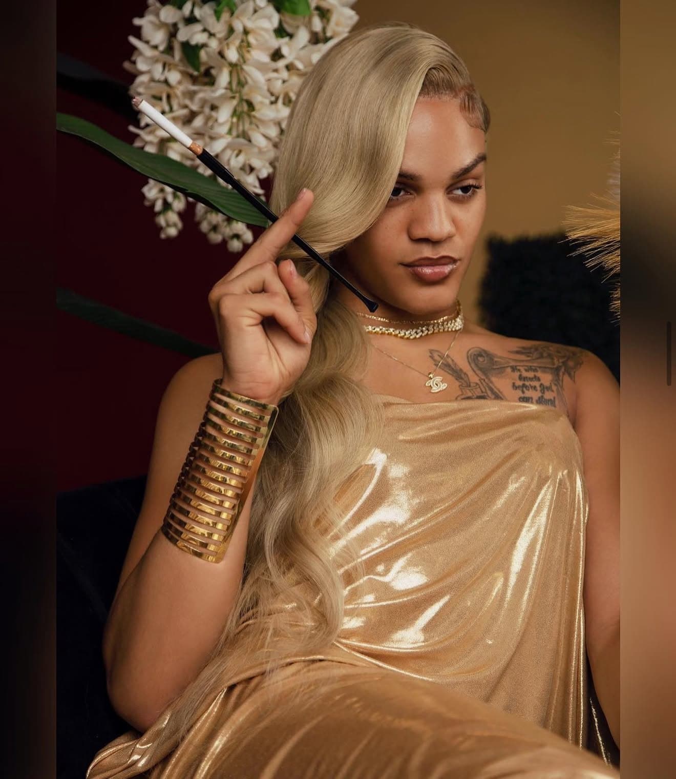 Quality in a gold gown, long blonde waves swept over one shoulder, looking into the lens