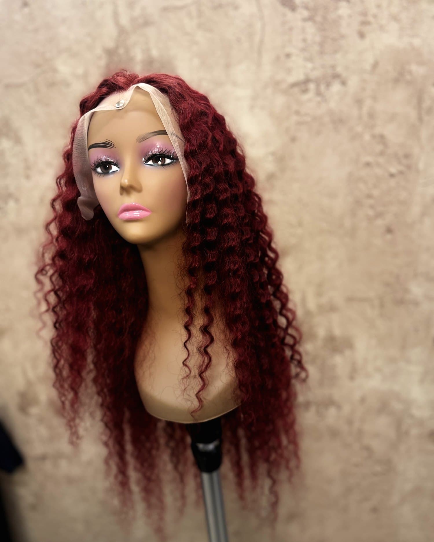 Burgundy curly lace unit on a stand, seen from the front.
