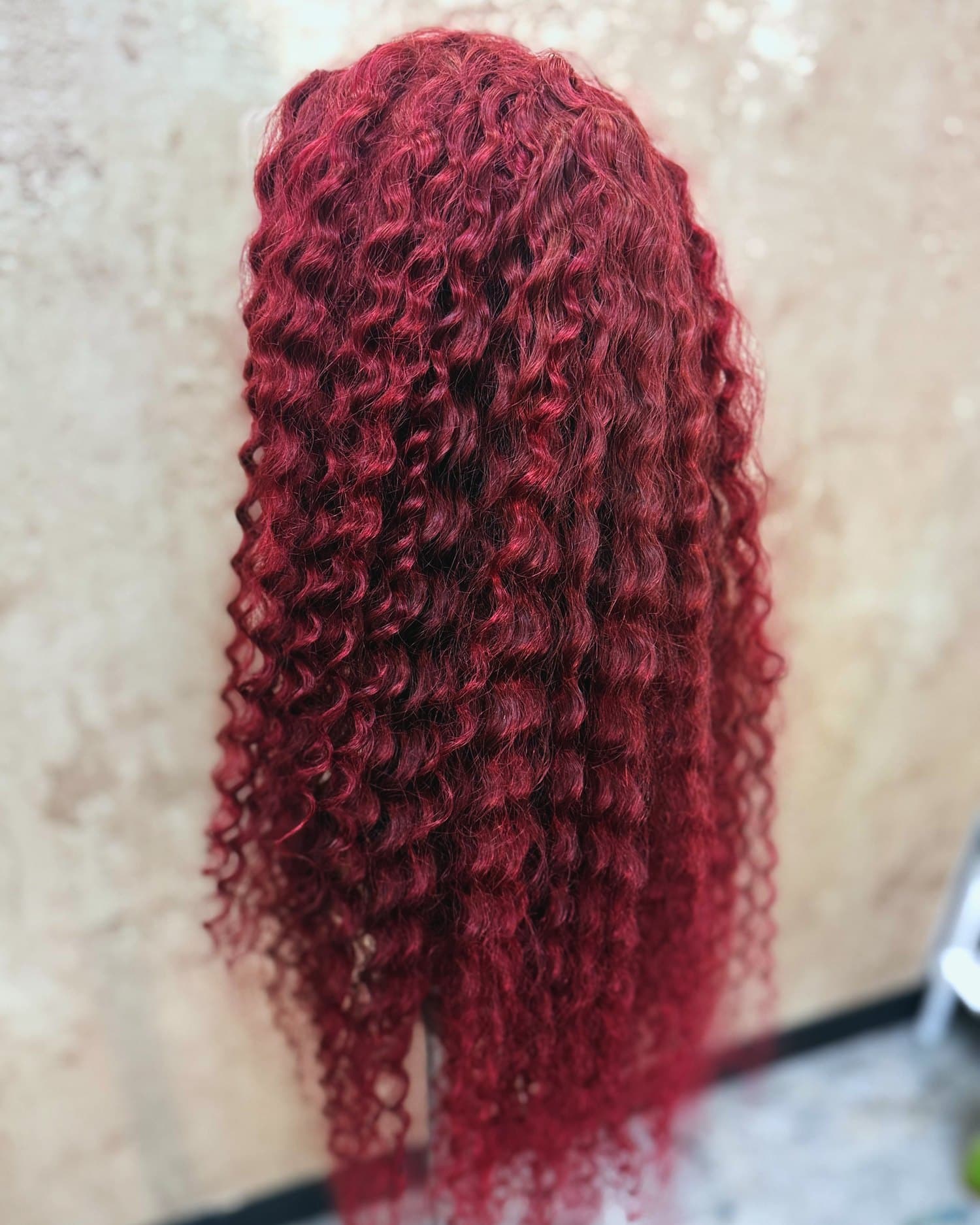 The same burgundy curly unit from behind, showing the length and density.